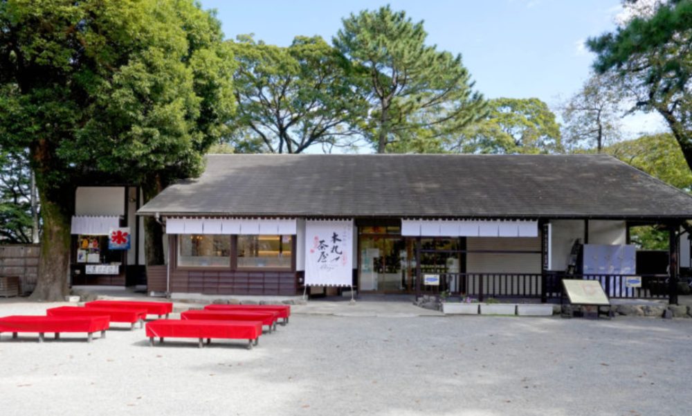 本丸茶屋の店構えの写真。のれんが掛かり、店先に赤い腰掛けが並んでいる